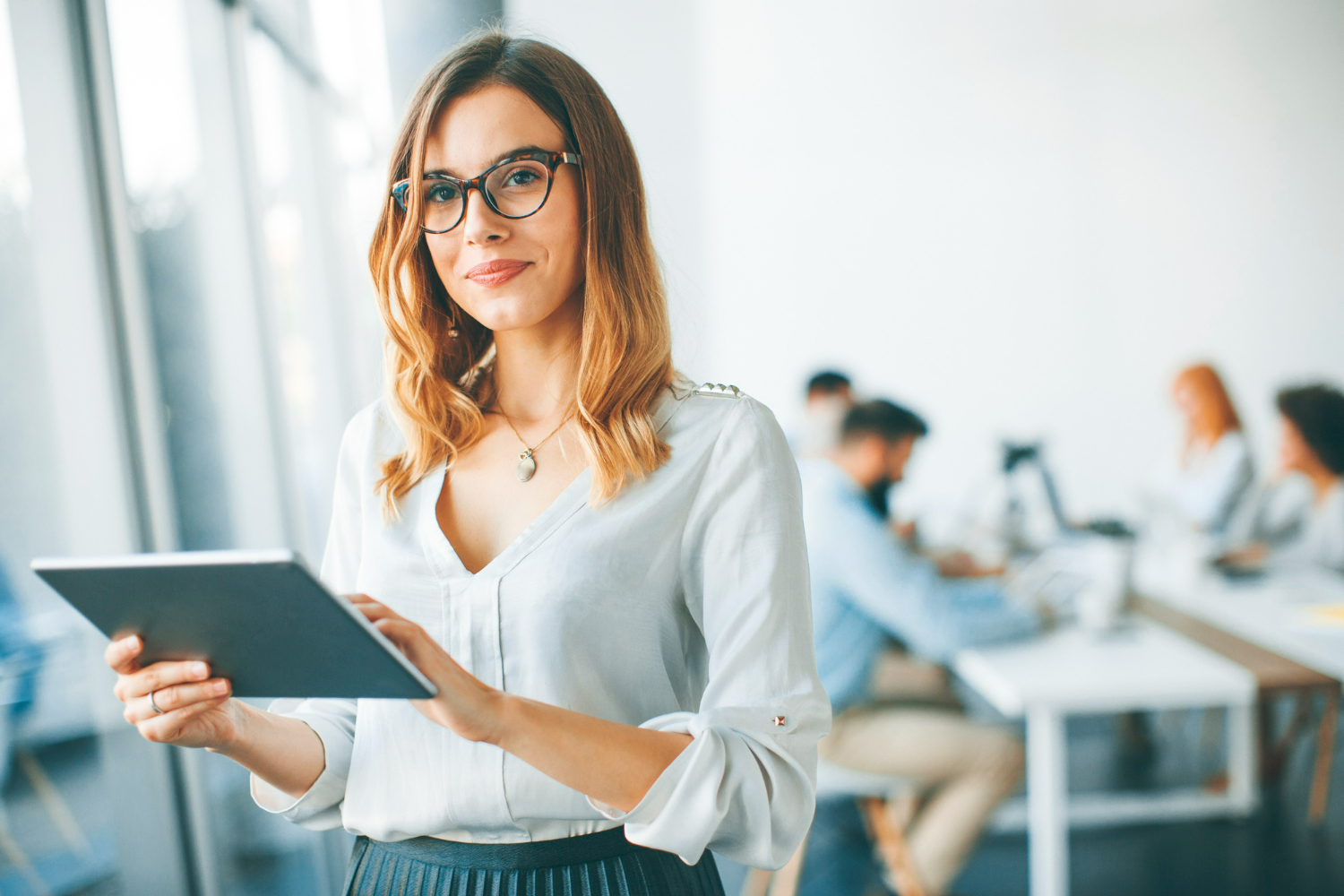 elegant businesswoman standing in office with digital tablet