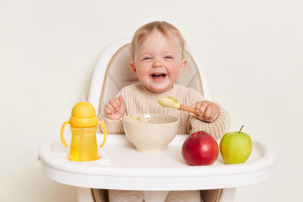 bebe souriant mange dans sa chaise haute