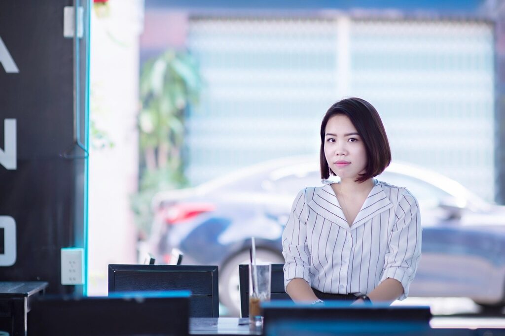 Jeune femme en tenue professionnelle dans un café moderne, représentant une étudiante en alternance à l’international